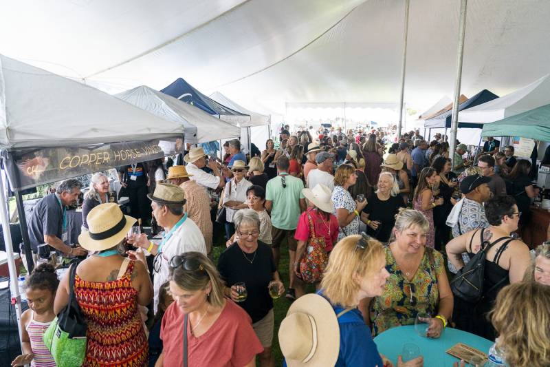 A crowd of people stand underneath a tent tasting wine at Sedona WIneFest.